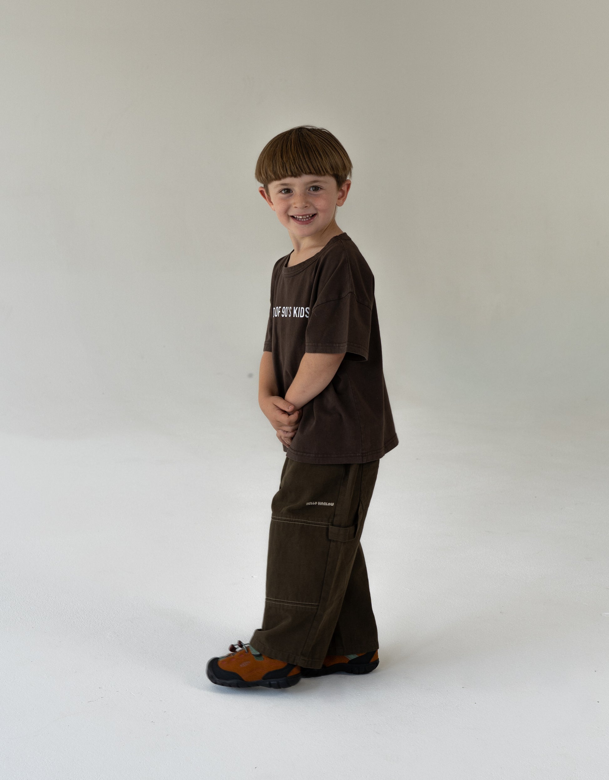 Child wearing a brown outfit with a logo, oversized kids clothing, brown canvas pants for kidswear and brown tee for kids oversized 