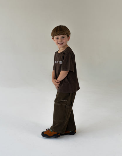 Child wearing a brown outfit with a logo, oversized kids clothing, brown canvas pants for kidswear and brown tee for kids oversized 