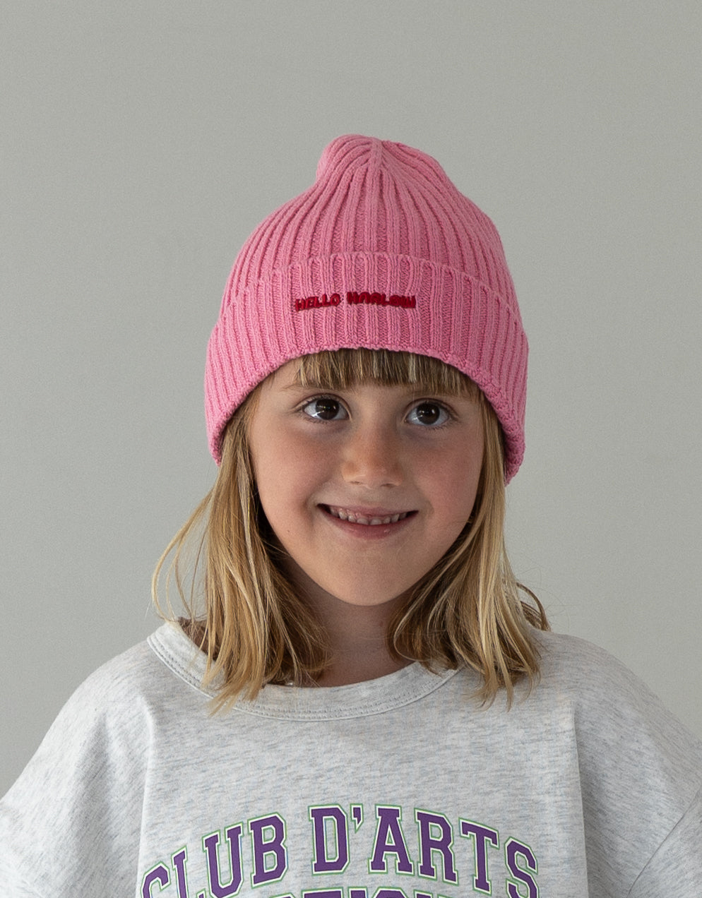 child wearing pink cotton beanie with embroidered logo
