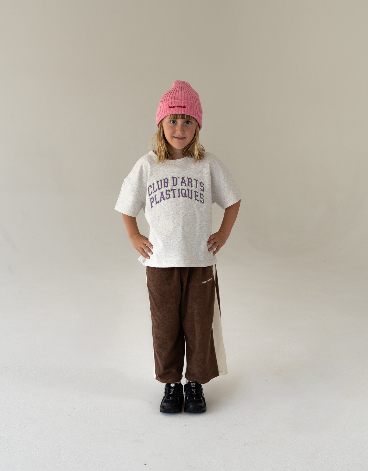 Child wearing oversized artsy t-shirt in grey with varsity logo