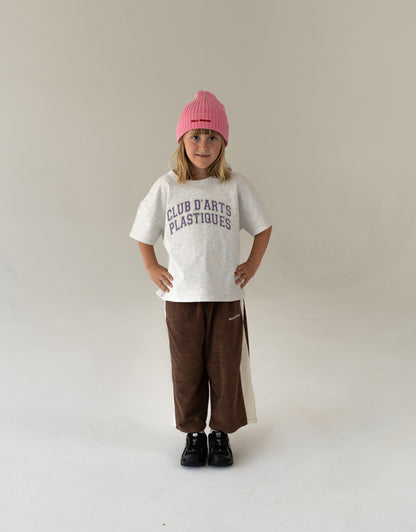 Child wearing oversized artsy t-shirt in grey with varsity logo